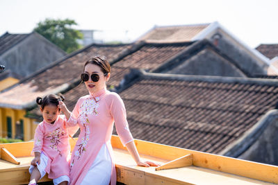 Mother and daughter with vietnam culture traditional dress standing at the rooftop in hoi an.