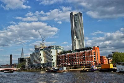 View of city at waterfront against cloudy sky