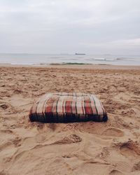 Deck chairs on beach against sky