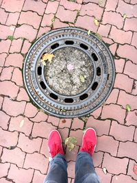 Low section of person standing by manhole lid on footpath