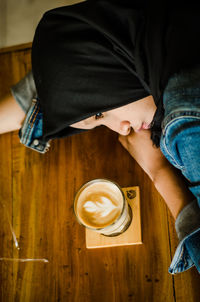 High angle view young woman by coffee cup on table