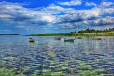 Boats sailing in sea against cloudy sky