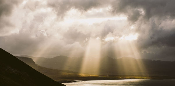 Sunlight streaming through clouds over landscape