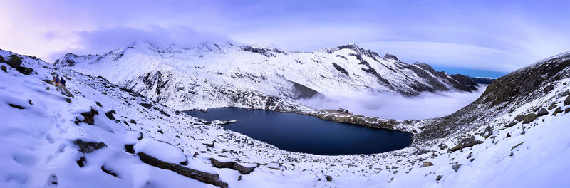 Scenic view of alpine lake surrounded by snowcapped mountains.