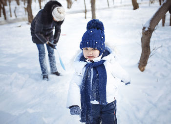 Portrait of cute daughter with mother on snowy field