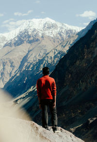 Rear view of man standing on snowcapped mountain