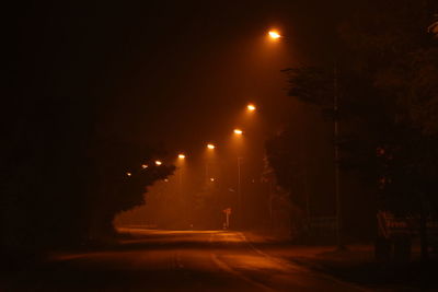 Illuminated road against sky at night