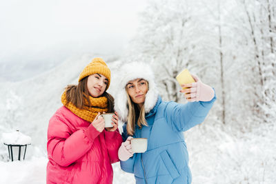 Two female friends make a selfie on a mobile in the winter in the mountains, wanderlust