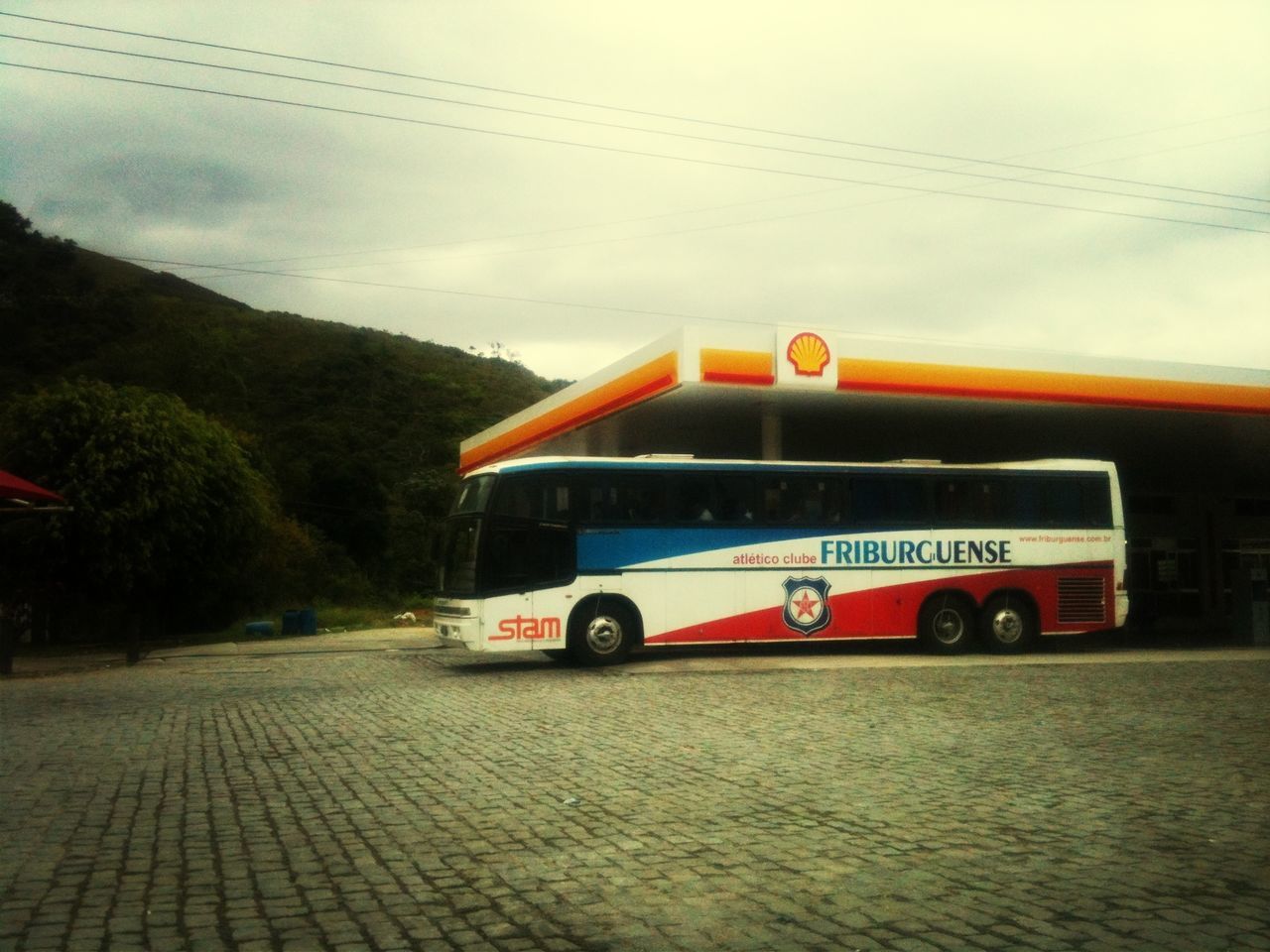 transportation, sky, mode of transport, text, communication, rail transportation, railroad track, train - vehicle, western script, land vehicle, tree, road, car, no people, public transportation, outdoors, day, power line, street, travel