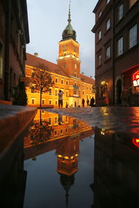Reflection of royal castle clock tower in puddle