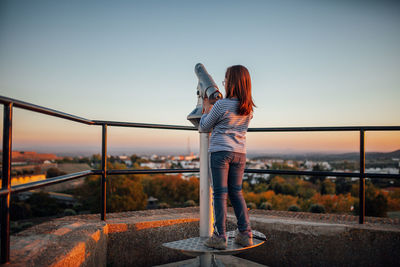 Woman standing by bridge against clear sky in city