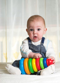 Portrait of cute baby boy with toys on bed