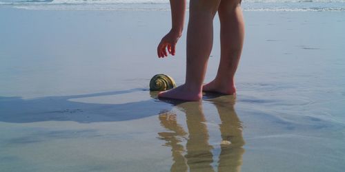 Low section of woman standing on wet beach