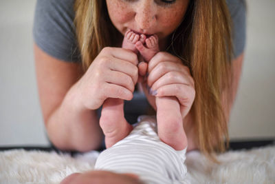 Midsection of mother holding baby boy feet