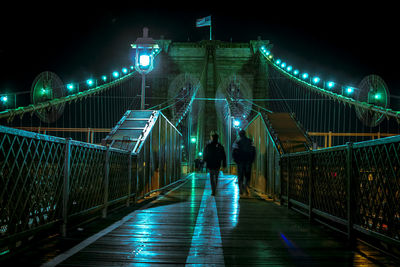 People on illuminated bridge at night