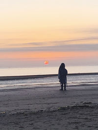 Silhouette people on beach against sky during sunset