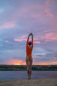 Rear view of young woman exercising during sunset