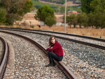 Girl sitting on railroad track