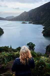 Rear view of woman looking at lake against mountain