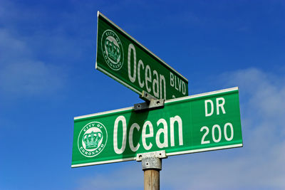 Low angle view of road sign against blue sky