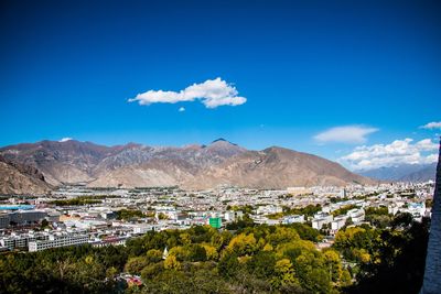 Scenic view of townscape and mountains against blue sky