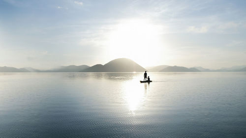 Silhouette man in sea against sky