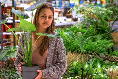 Portrait of young woman holding plant