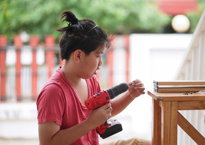 Side view of girl holding wood