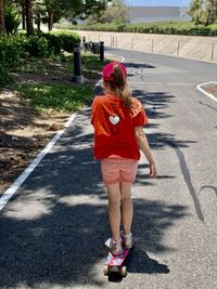 Rear view of woman standing on road in city