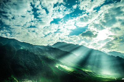Sunlight streaming through clouds over landscape