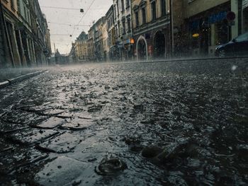 Empty road amidst buildings in city during rain