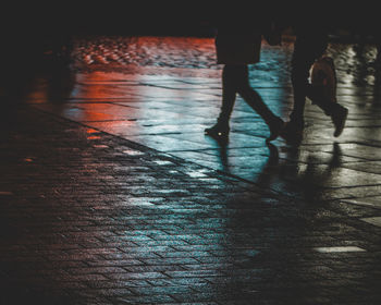 Low section of woman walking on wet street