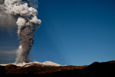 Smoke emitting from volcanic mountain against sky