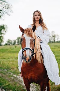 Young woman riding horse on field