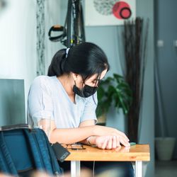 Young woman using mobile phone while sitting on table at home