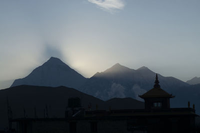 Silhouette building and mountains against sky