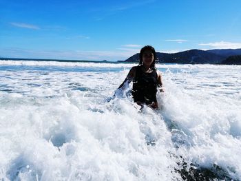 Portrait of smiling young woman in sea against sky