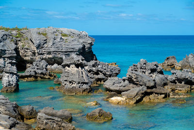 Rocks on sea shore against blue sky