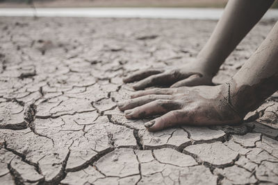 Cropped hand of women on arid land by faucet