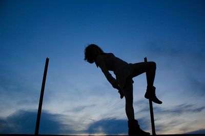 Low angle view of silhouette man standing against blue sky