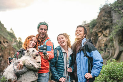 Hikers taking selfie with dog on mountain