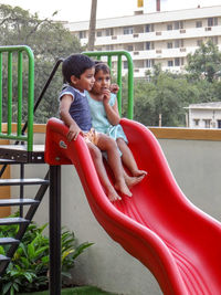Happy siblings on slide at playground