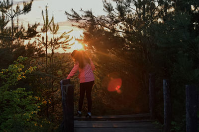 Rear view of woman standing by tree against sky