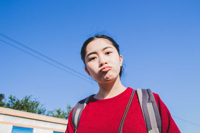 Portrait of beautiful woman standing against clear blue sky