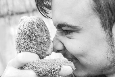 Close-up of young man playing with teddy bear