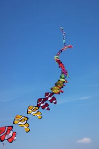 Low angle view of kites against clear blue sky