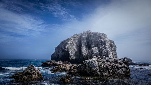 Rock formation in sea against sky