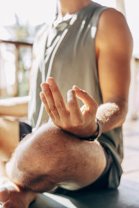 Low section of man practicing mudra position while doing yoga at wellness resort