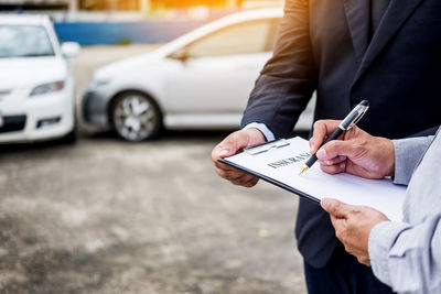 Midsection of man signing car insurance form