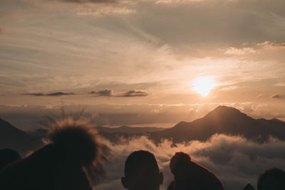 Silhouette people on mountain against sky during sunset